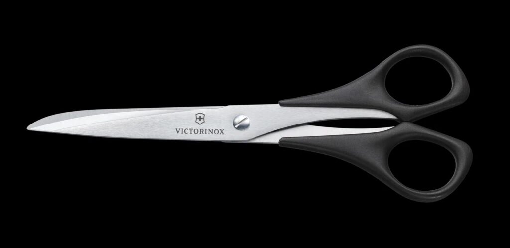 Pair of stainless steel scissors with black plastic handles, Victorinox logo visible on the blade on a white background.